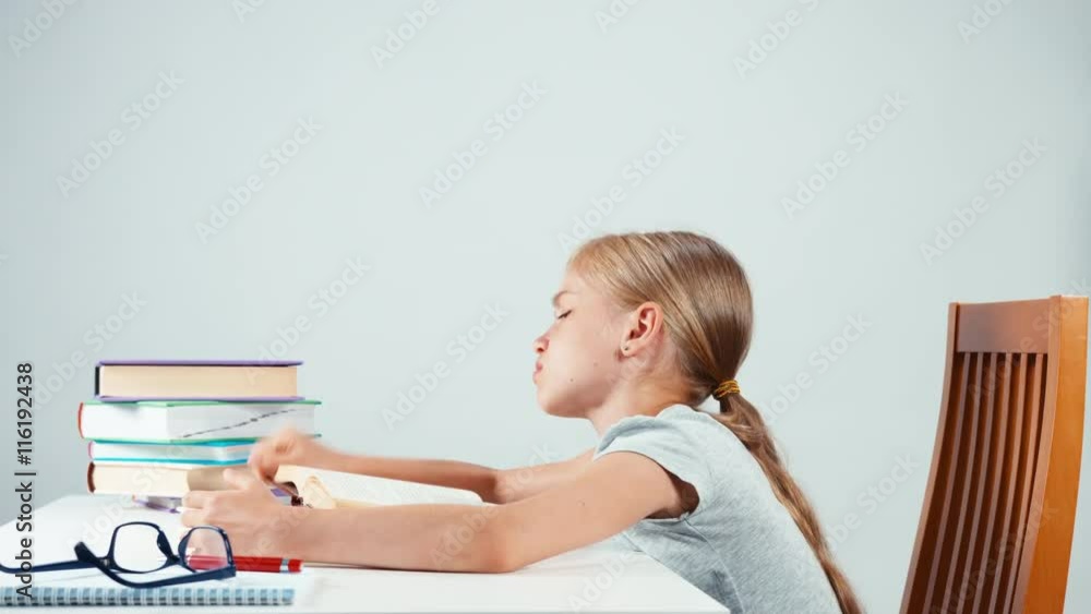 Portrait sad girl child student sitting in the table and with a sadly face. Isolated on white Portrait sad girl child student sitting in the table and with a sadly face. Isolated on white
