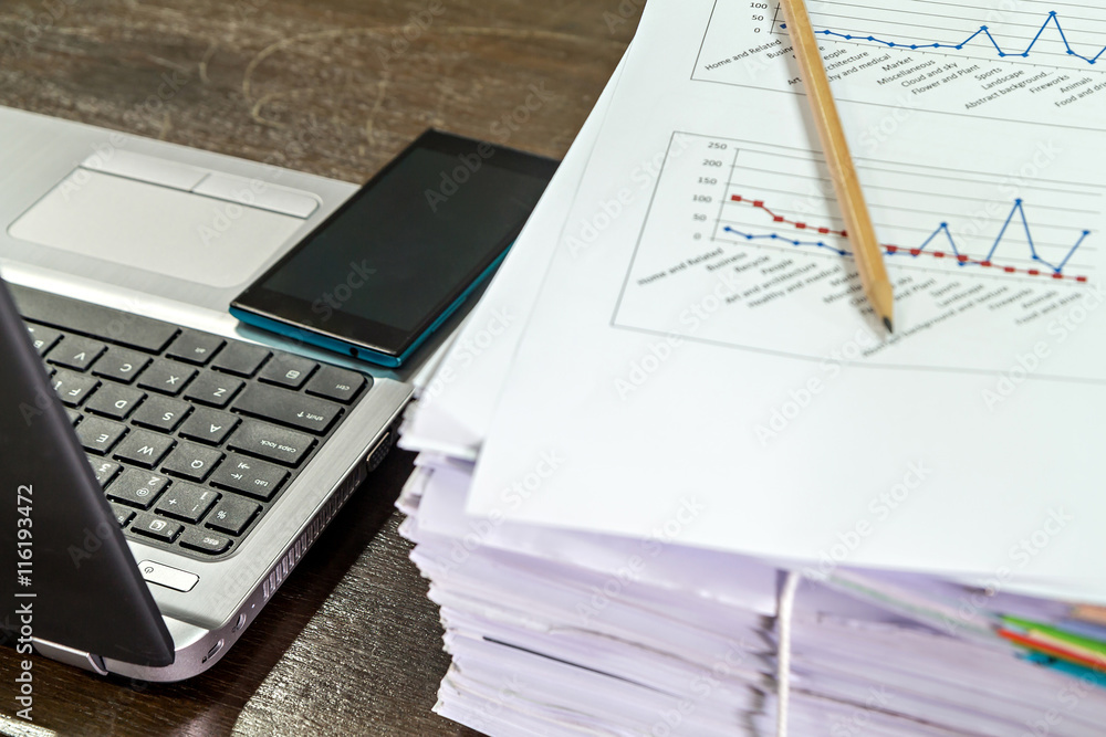 Smartphones on laptop near documents stack and pencil Smartphones on laptop near documents stack and pencil