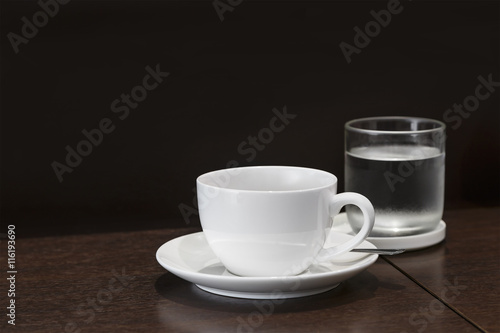 Cup of coffee with glass and water on wooden table