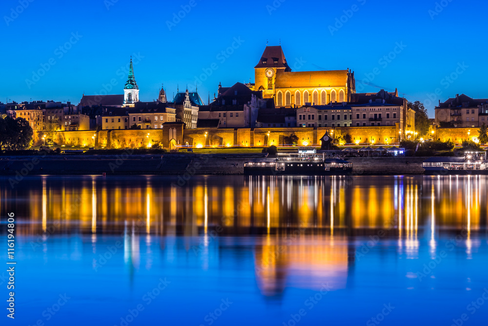 Torun Old Town at night reflected in Vistula river, Poland