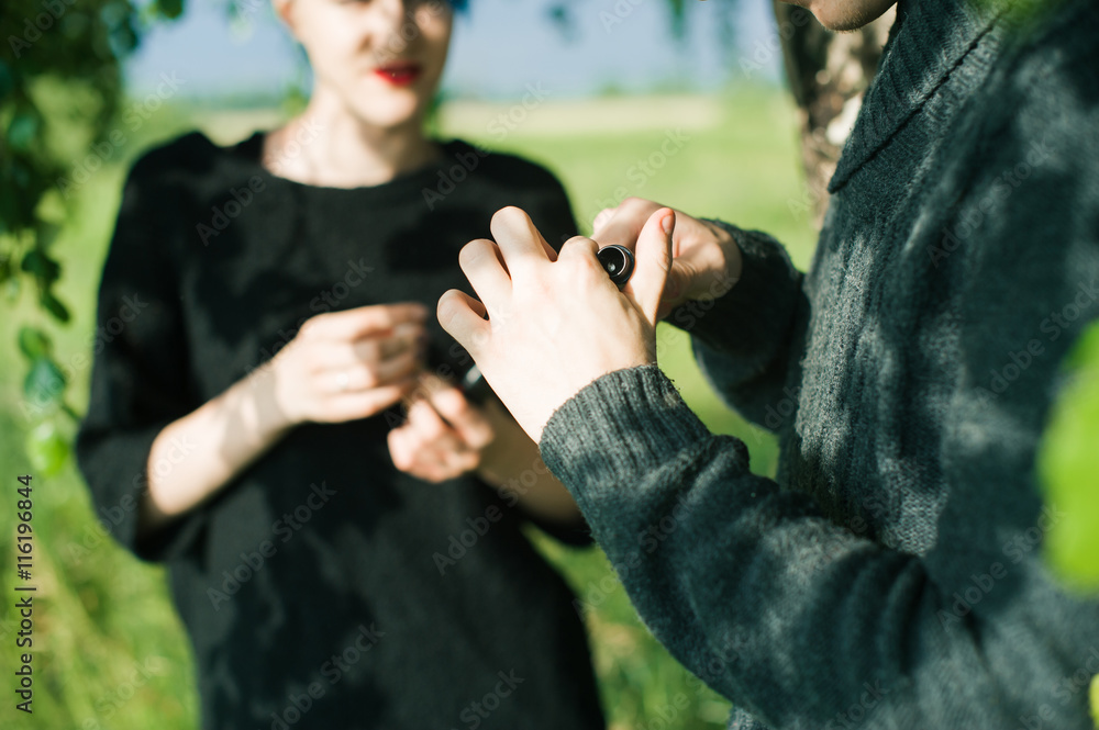 young couple with dyed hair smoking electronic cigarettes in nature young couple with dyed hair smoking electronic cigarettes in nature