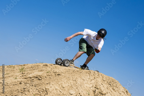 Skateboarder doing a jumping trick at skateboard park with mountainboard