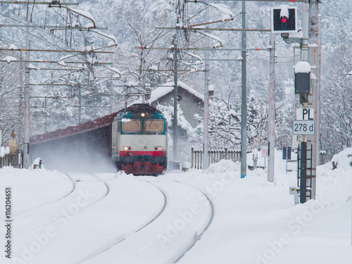 Freight train running on the railway tracks while is snowing