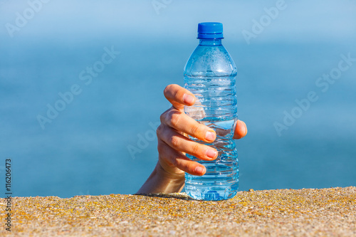 Male hand taking away water plastic bottle outdoor
