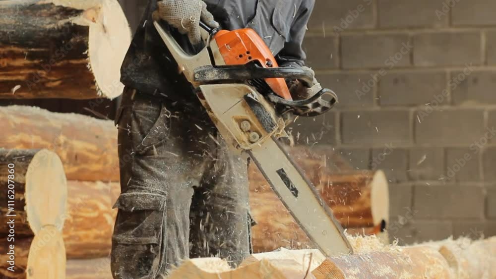 Man cuts off beam chainsaw for future log cabin. Construction works with a wooden structure Man cuts off beam chainsaw for future log cabin. Construction works with a wooden structure