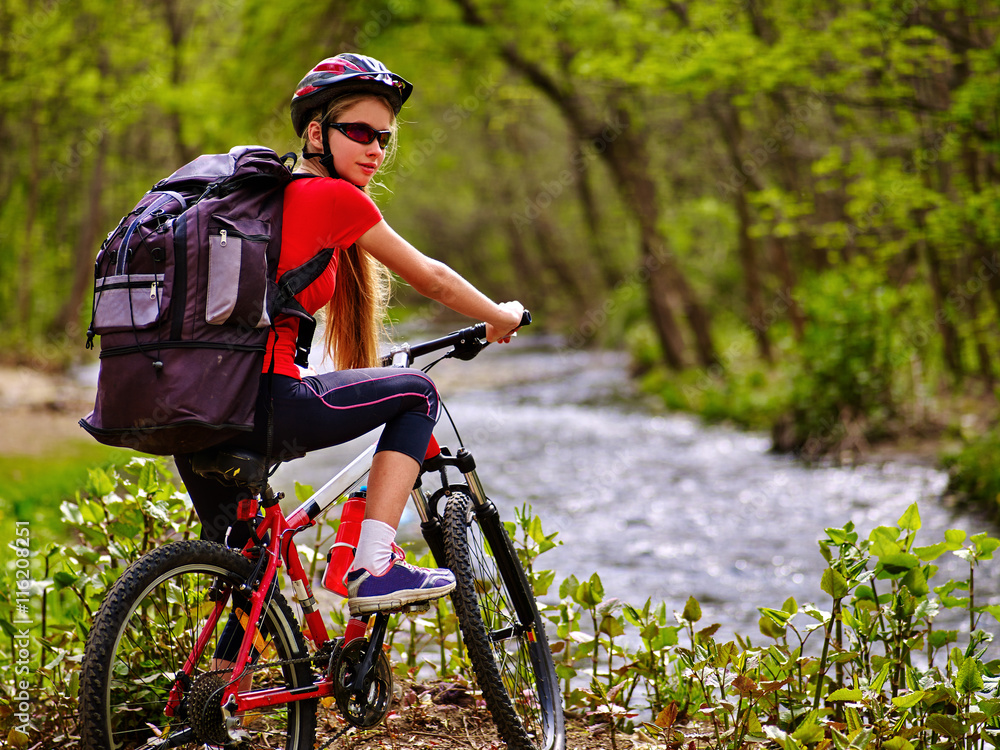 Obraz premium Bicycle girl. Girl with big rucksack rides bicycle. Girl cycling fording throught water . Cycling trip is good for health. Cyclist turned back.