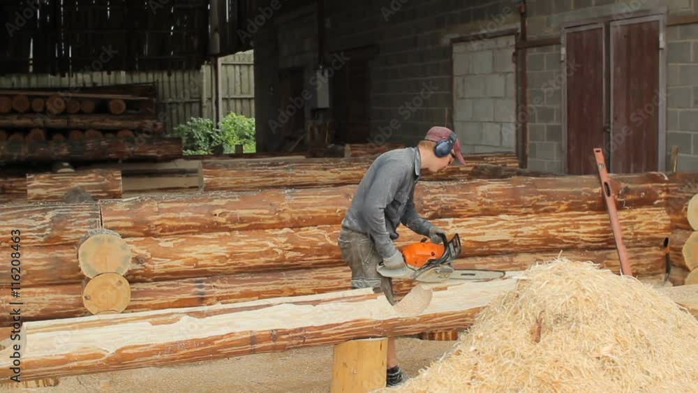 Man cuts off beam chainsaw for future home. Construction works with a wooden structure Man cuts off beam chainsaw for future home. Construction works with a wooden structure