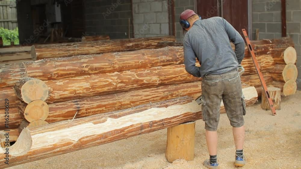 Man cuts off beam chainsaw for future log cabin. Construction works with a wooden structure Man cuts off beam chainsaw for future log cabin. Construction works with a wooden structure