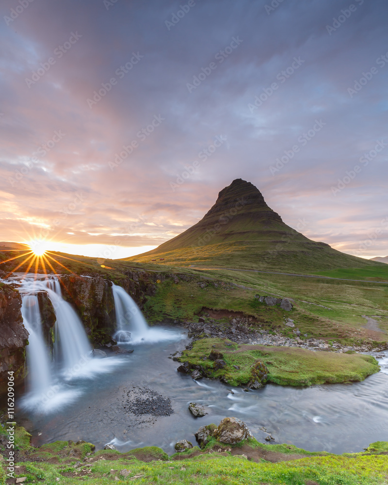 Fototapeta premium Amazing top of Kirkjufellsfoss waterfall with Kirkjufell mountain in the background on the north coast of Iceland's Snaefellsnes peninsula taken white a long shutter speed. 