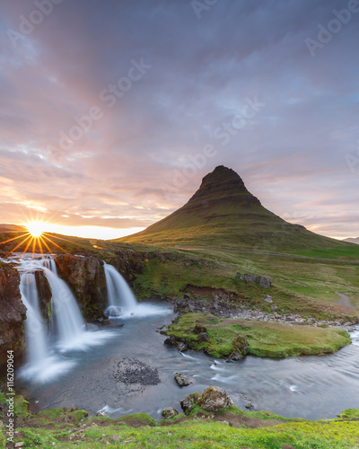 Amazing top of Kirkjufellsfoss waterfall with Kirkjufell mountain in the background on the north coast of Iceland s Snaefellsnes peninsula taken white a long shutter speed.  