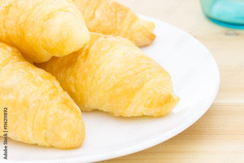 Croissant or Bread on White Dish on Wood Table and Glass Croissant or Bread on White Dish on Wood Table and Glass
