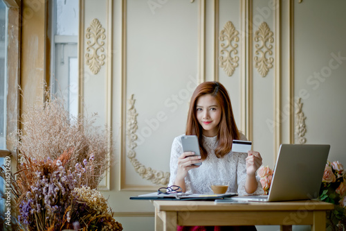 Happy woman shopping online, holding credit card. photo