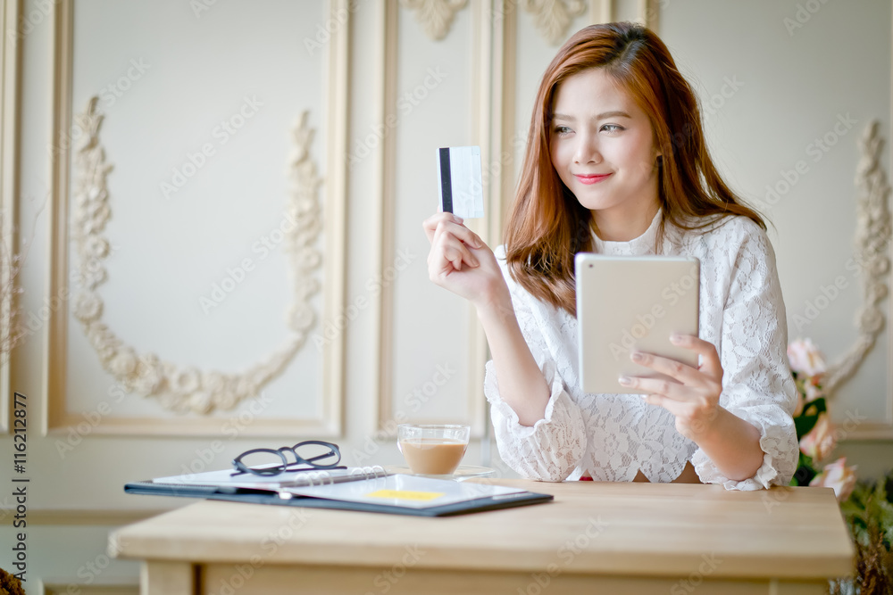 Happy woman shopping online, holding credit card, using tablet c Happy woman shopping online, holding credit card, using tablet c