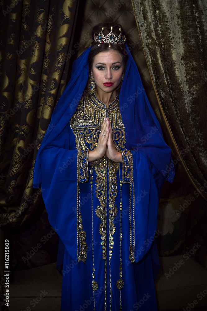 woman in the Arab national blue dress, hands clasped