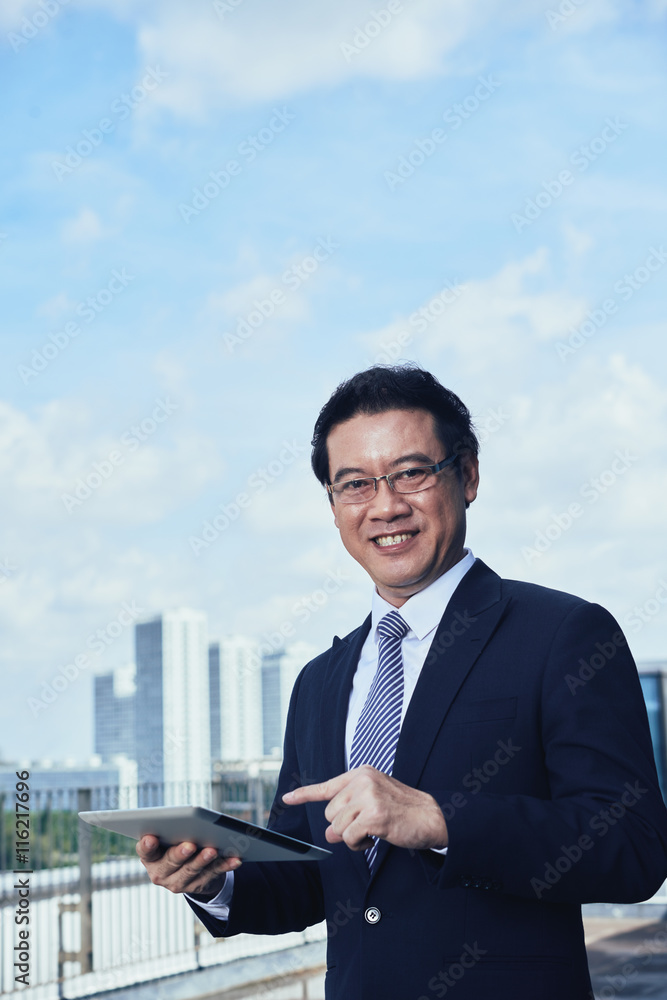 Portrait of cheerful Asian businessman with tablet computer
