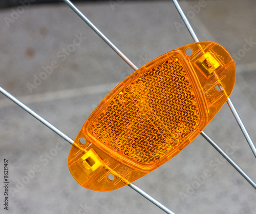 Orange reflector on bicycle wheel spokes