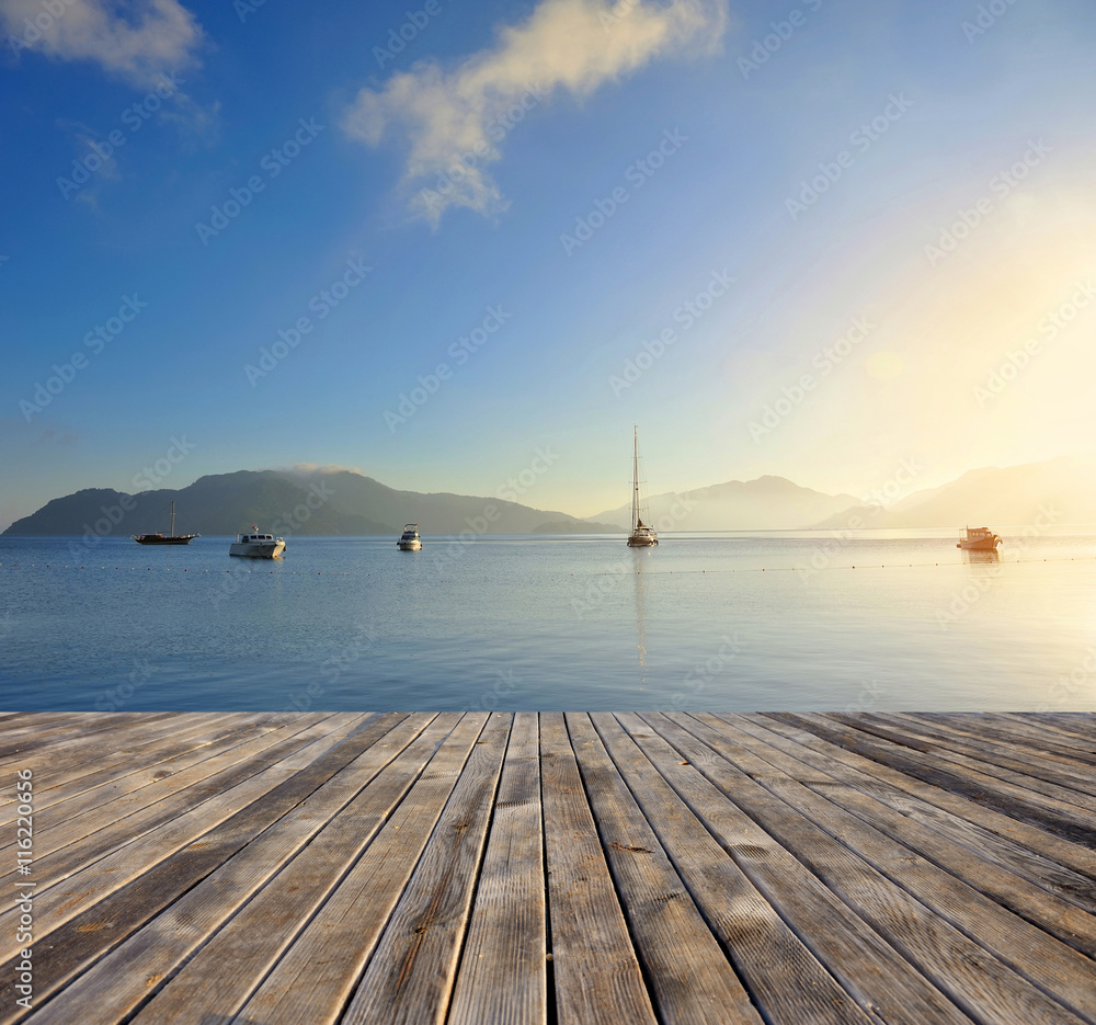 Beautiful morning seascape with boats and mountains in the background