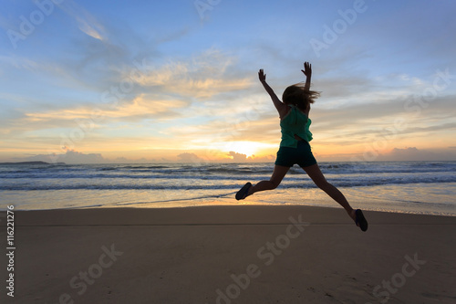 woman traveller happy jumping on the beach with sunrise