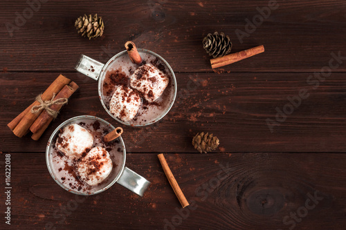 Canvas Print Hot chocolate in a mugs, marshmallows, cinnamon sticks and fir cones, top view,