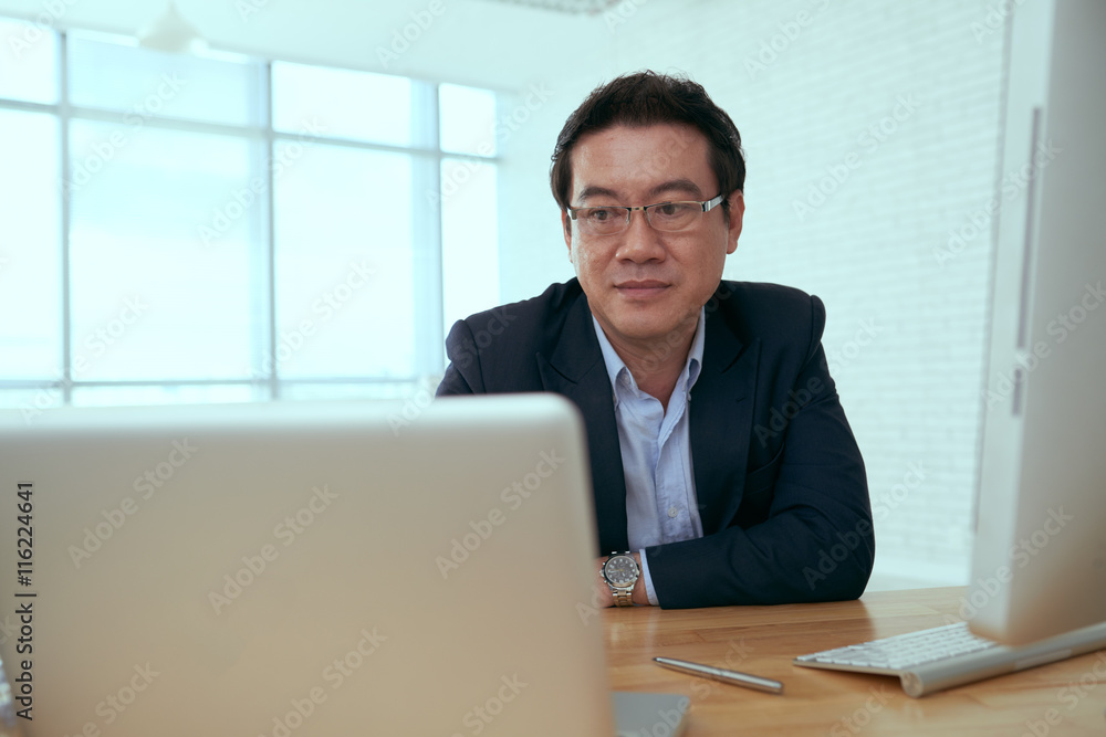 Portrait of Vietnamese entrepreneur watching something on laptop screen Portrait of Vietnamese entrepreneur watching something on laptop screen