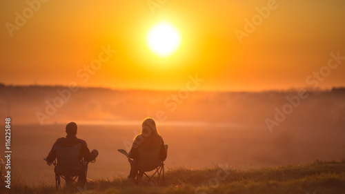 Photography The two people sit against the background of sunset