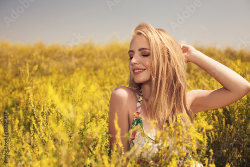 Blonde sexy young beautiful girl in the field yellow flowers