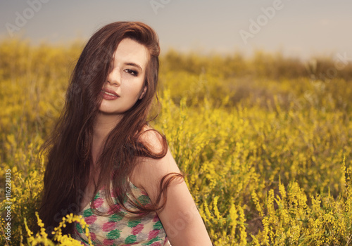 Young beauty woman in the park with yellow flowers photo