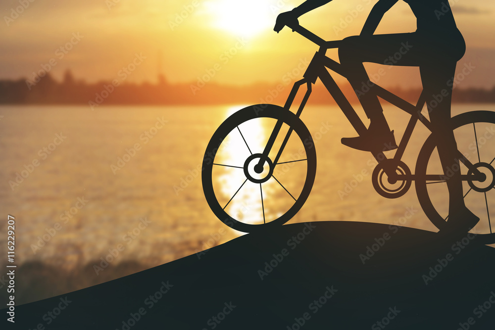 Fototapeta premium Silhouette of a woman on muontain bike, sunset.Vintage color