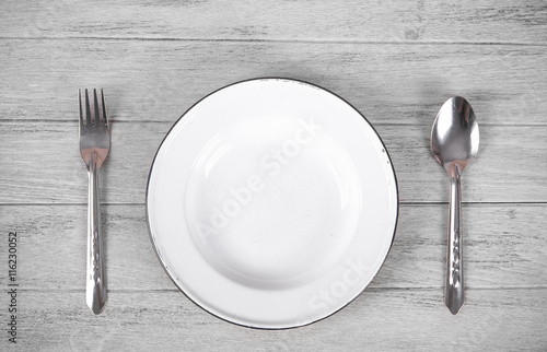 white plate, spoon and fork on old white wooden table