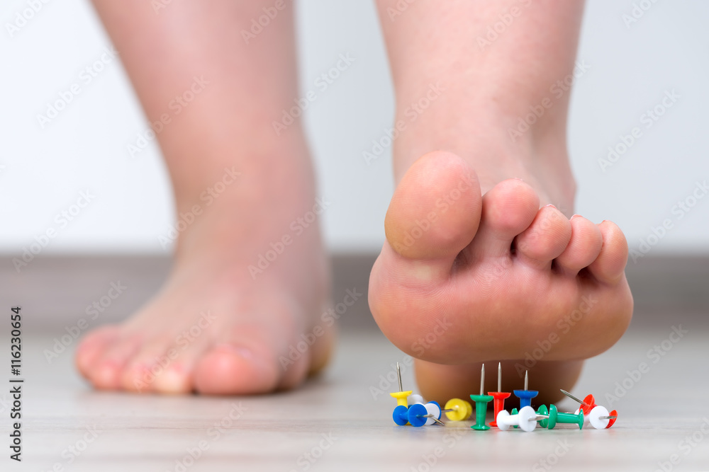 Female foot above colored pushpin Female foot above colored pushpin
