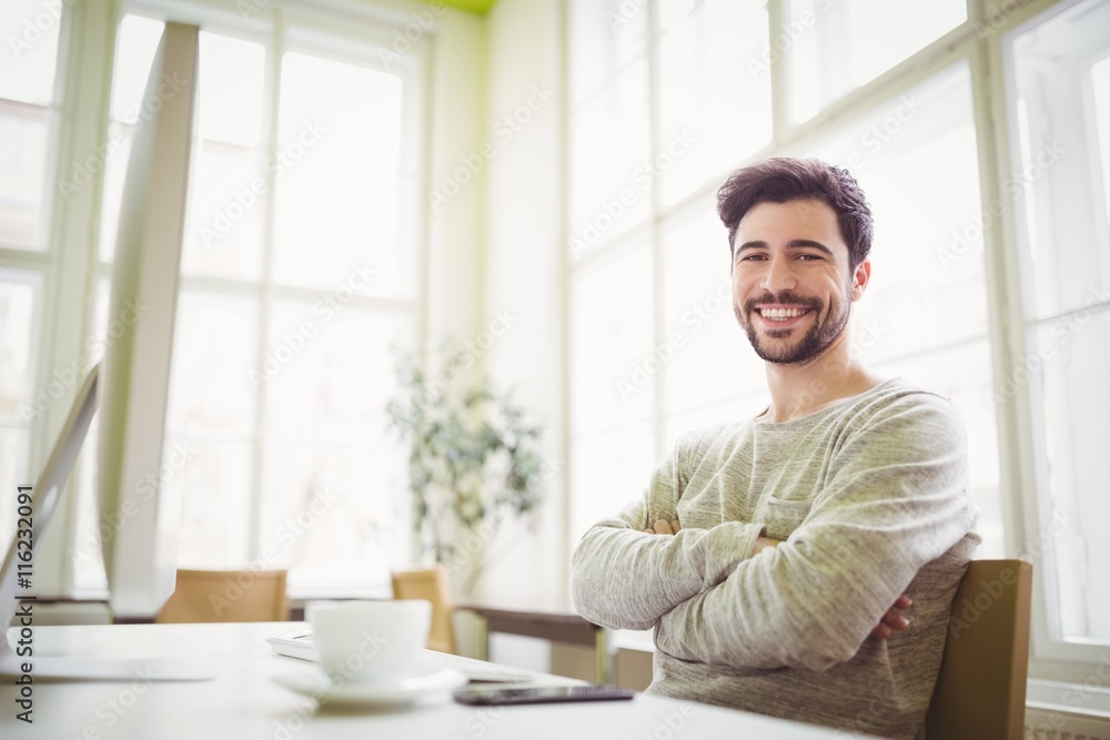 Smiling businessman sitting at desk in office Smiling businessman sitting at desk in office