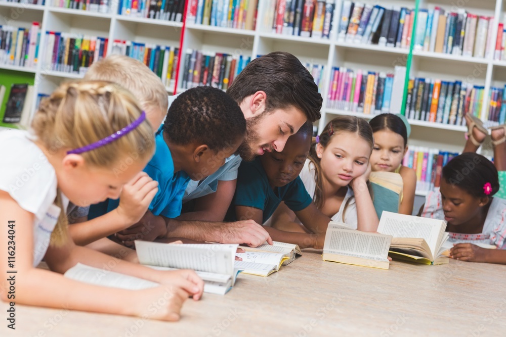 Teacher and kids lying on floor reading book in library Teacher and kids lying on floor reading book in library