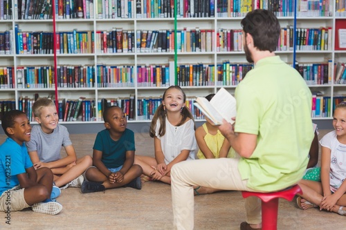 Obraz na plátně Teacher teaching kids in library
