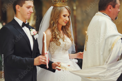 Groom and bride hold  priest cassock during an engagement ceremo photo