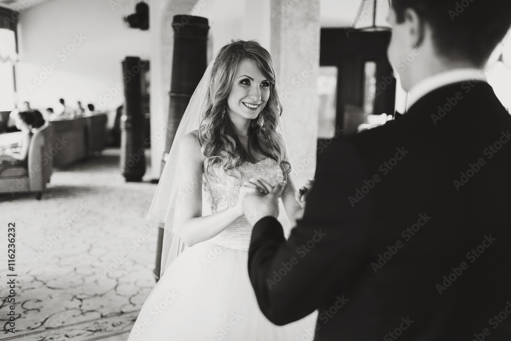 Naklejka premium Bride smiles while groom holds her arms tenderly