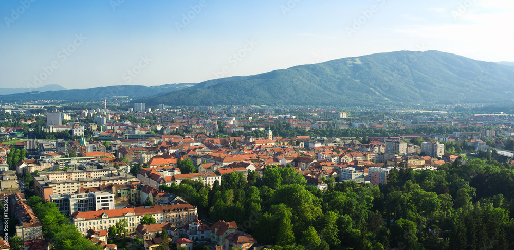 Pseudo aerial cityscape scenery of Maribor from Piramida Hill. City park, historical old town centre / center and Pohorje mountain. Summer season and yellow light of sunset