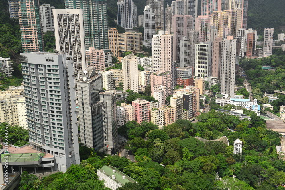 Crowded Hong Kong scene with tightly packed skyscrapers and apartment buildings with green tropical mountain background