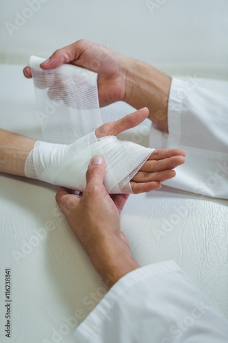 Konstfotografi Physiotherapist putting bandage on injured hand of patient