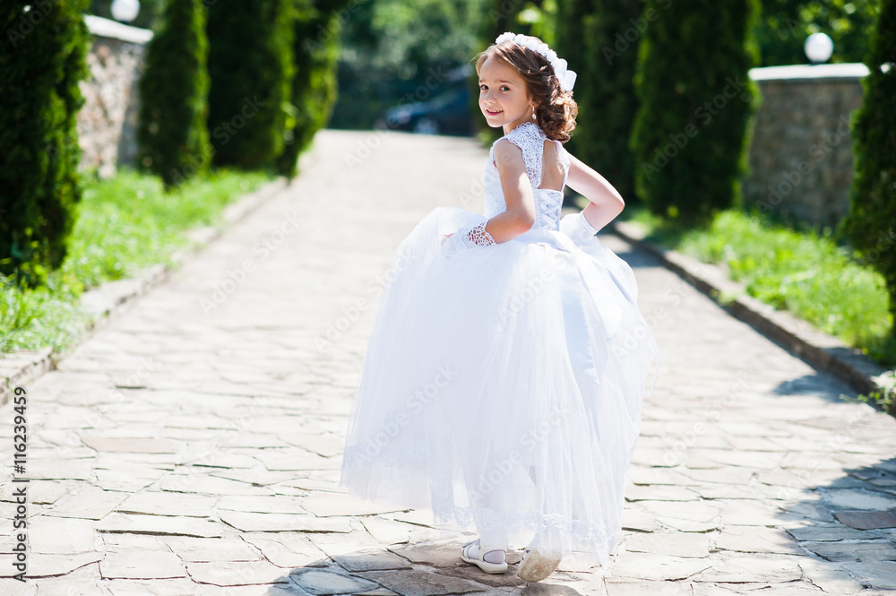 Portrait of cute little girl on white dress and wreath of first