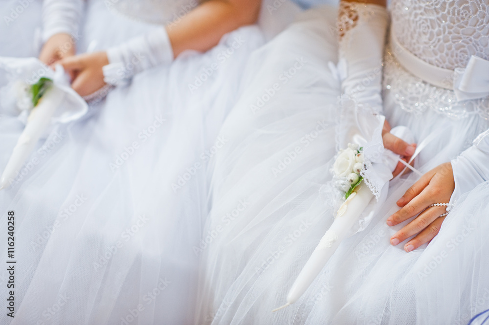 Hands with candles of little girls on first holy communion Hands with candles of little girls on first holy communion