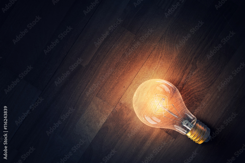 Light bulb on wooden surface . Mixed media Light bulb on wooden surface . Mixed media