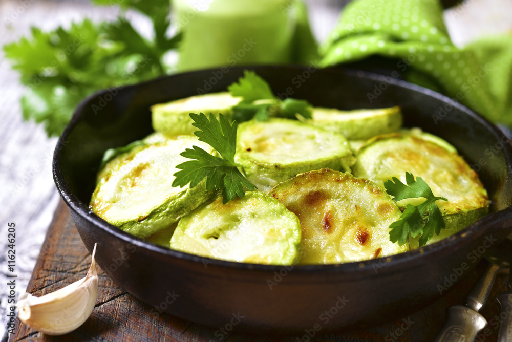 Fried zucchini in a skillet with spicy green sauce.