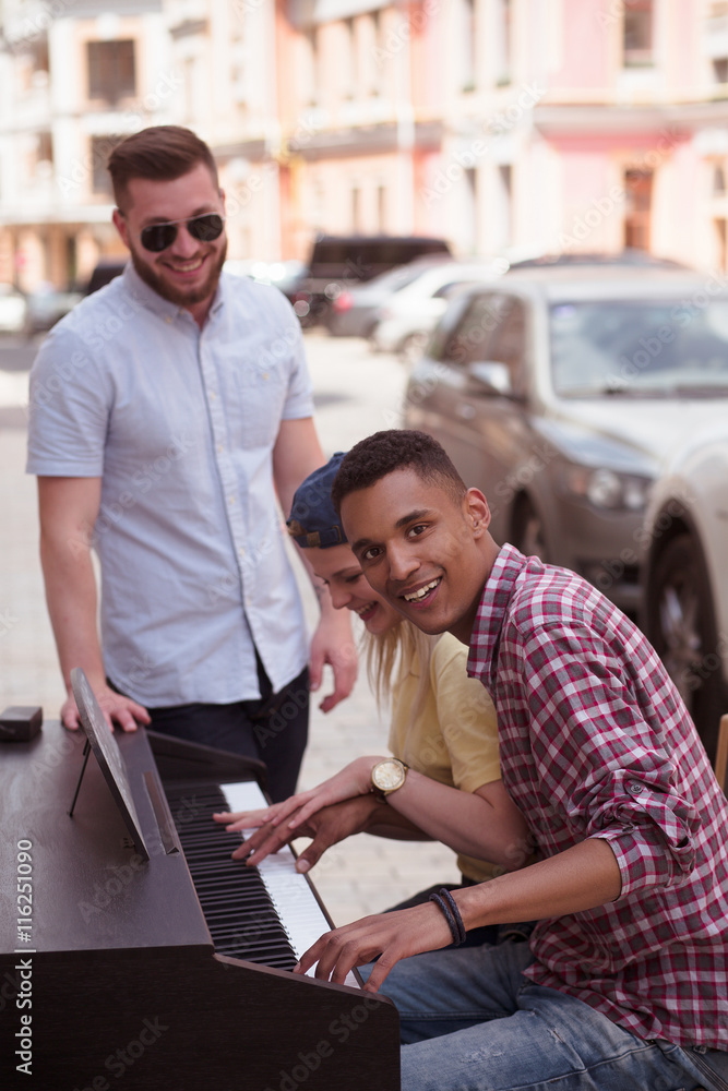 Closeup picture of keyboard of piano. Black man playing piano and looking  at camera while his best friends standing near him. Stock Photo | Adobe  Stock