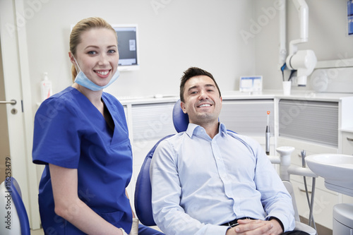 happy female dentist with man patient at clinic