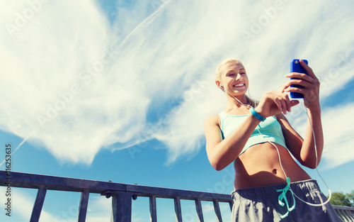 happy woman with smartphone and earphones outdoors