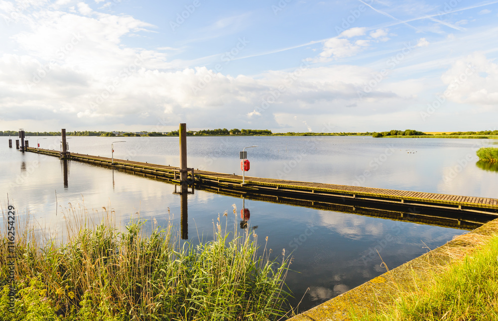 Long wooden jetty in a lake with a mirror smooth surface