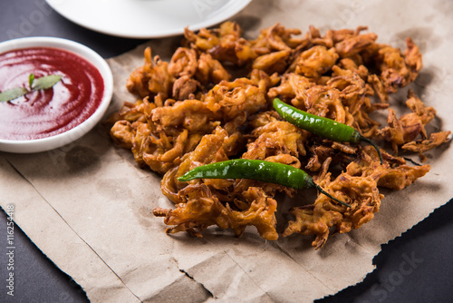 Crispy onion bhaji or kanda bhaji or fried onion pakore or pakode, delicious street food, favourite indian snack in monsoon served with hot tea photo