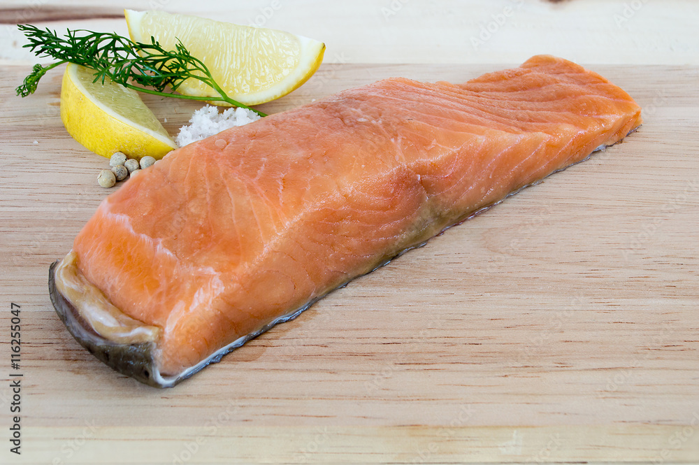 Salmon fillets fresh with lemon coriander salt and pepper on a wooden floor. Salmon fillets fresh with lemon coriander salt and pepper on a wooden floor.