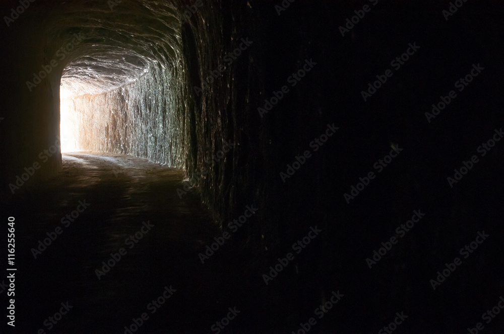 Dark road in a natural rocky tunnel and the light of the exit Dark road in a natural rocky tunnel and the light of the exit