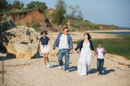 Father, mother, son and daughter on the beach. Sunset, sunlight, beach coast family